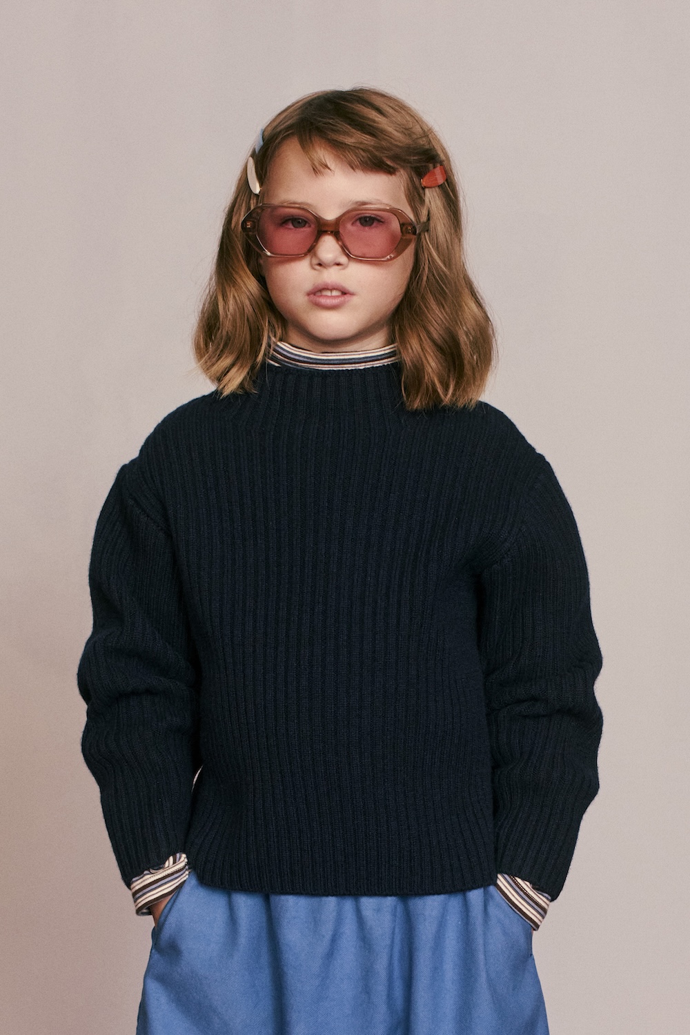 Child wearing a navy ribbed sweater, striped shirt collar and pink-tinted sunglasses from the Caramel for Zara collection.